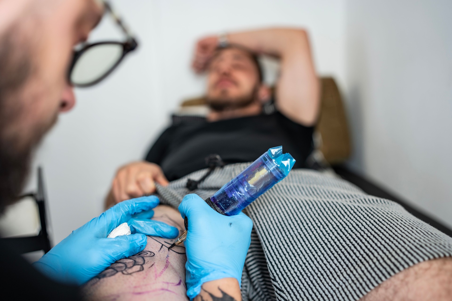 Tatoueur professionnel créant un motif d’encre sur la peau du client en studio