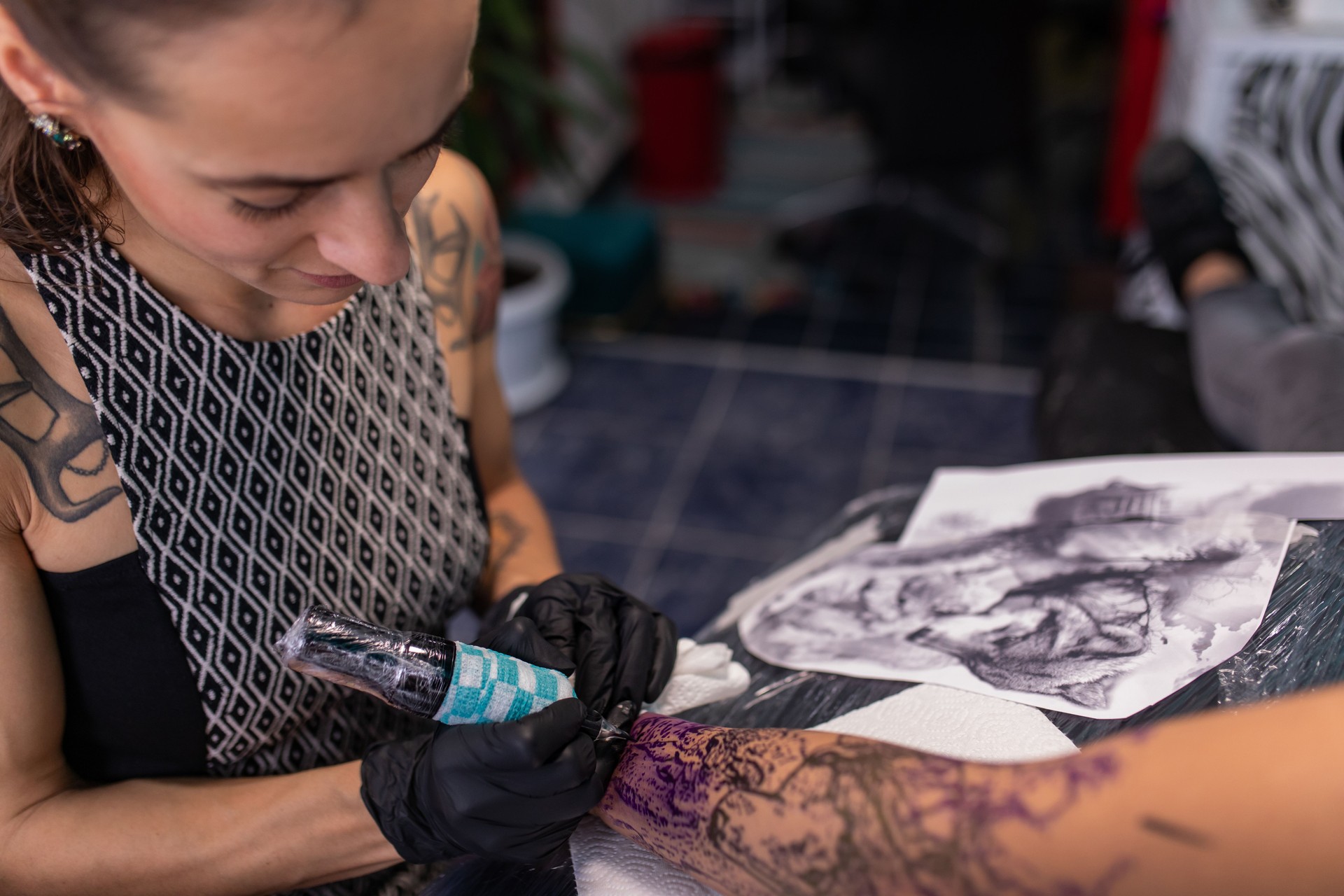 Photographie rapprochée d’une jeune tatoueuse qui travaille dans son studio.